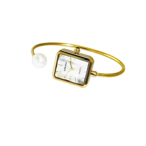 Elegante orologio da polso quadrato dorato con perla bianca su sfondo bianco puro