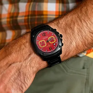 Close-up detail of a men's sports watch with a bold red dial and black metal strap