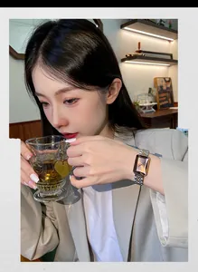 Elegant women's rectangular gold watch shown on wrist in a cozy lifestyle setting