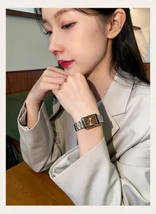 Detail of a CILOA luxury gold and silver square face watch worn by a female model