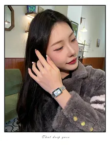 Detailed shot of a model wearing a minimalist luxury rectangular women's watch silver strap