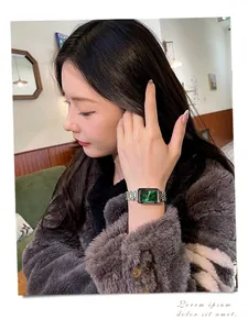 Detailed view of an elegant rectangular watch with green sunray dial on a woman's wrist