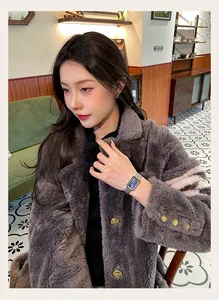 Close-up of elegant silver rectangular watch worn by a model in a luxury winter coat