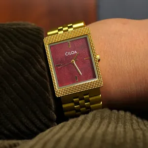 Gros plan d'une montre carrée rétro CILOA pour homme avec cadran rouge et bracelet doré