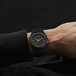 Detalle de un reloj de hombre negro mate con números arábigo-índicos puesto en la muñeca.