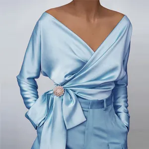 Detail of elegant light blue satin wrap blouse with V-neck and crystal brooch bow
