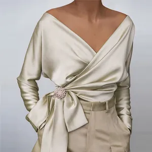 Close-up view of an elegant champagne satin V-neck wrap blouse featuring a stylish bow tie waist