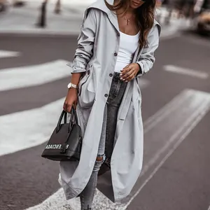 Detailed view of a light grey long trench coat for women with large lapels and button front.