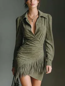 Detail view of an olive green suede mini dress with fringe hem and long sleeves.
