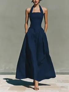 Elegant navy halter-neck maxi dress with side pockets and a pleated flared skirt