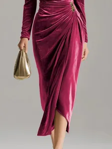 Detail of magenta velvet dress featuring elegant pleats and a gold waist ornament detail
