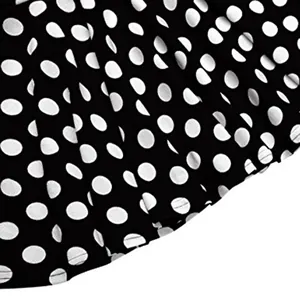 Gros plan du motif à pois blancs sur tissu noir d'une mini-jupe trapèze élégante
