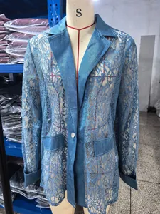 Dettaglio del pizzo floreale e patchwork di denim su una giacca blazer blu lunga.