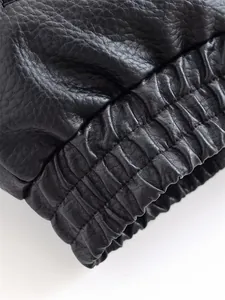 Macro detail showing the elastic ribbed hem texture on a black faux leather biker jacket