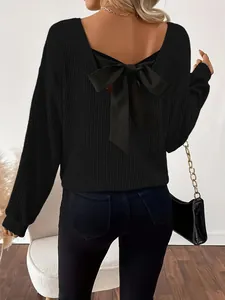 Vista de detalle de un jersey de punto negro con cuello en V y un gran lazo de raso elegante
