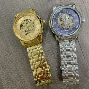 Top view of two Forsining men's skeleton automatic mechanical watches on a gray wooden background