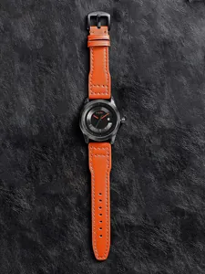 Nahaufnahme der TOMI Armbanduhr mit orangefarbenem Lederarmband und schwarzem Zifferblatt