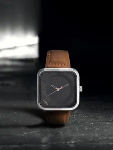 Gros plan de la montre à quartz TOMI avec boîtier carré argenté et bracelet en cuir.