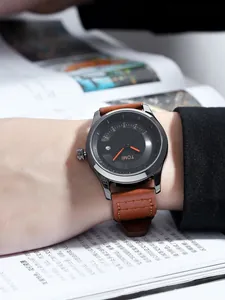 Detaillierte Nahaufnahme einer TOMI Modeuhr mit braunem Lederarmband und Datumsanzeige.