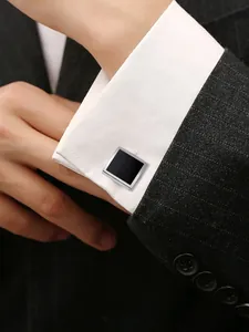 Gros plan de boutons de manchette carrés noirs et argentés sur une manche de chemise
