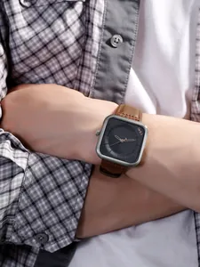 Détail d'une montre à quartz carrée TOMI avec bracelet en cuir marron au poignet.