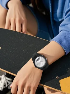 Gros plan de la montre de sport TOMI à double affichage au poignet sur fond de skateboard.