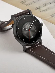 Vista dettagliata dell'orologio TOMI minimalista con quadrante nero e cinturino in pelle marrone.