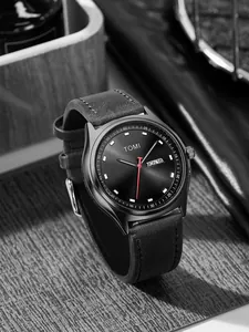 Close-up of TOMI minimalist black watch with day-date display and leather strap