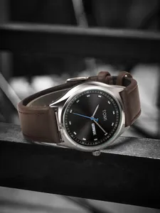 Close-up detail of TOMI minimalist watch with black dial and brown leather strap