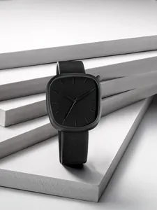 Vue détaillée d'une montre à quartz minimaliste noire en forme de galet avec bracelet en cuir