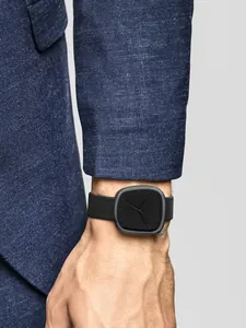 Gros plan d'une montre noire minimaliste en forme de galet avec une veste bleue