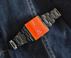 Close-up of trendy square men's watch featuring a vibrant orange face and black steel strap