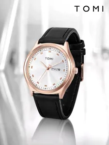 Close-up of TOMI rose gold watch with white dial, day-date window, and black strap.