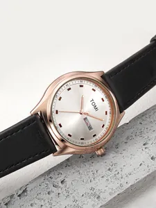 Close-up detail of TOMI rose gold watch with black leather strap and day-date display.