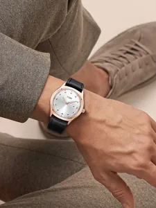 Lifestyle view of TOMI minimalist day-date watch with black leather strap on wrist.