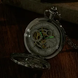 Gros plan d'une montre à gousset squelette vintage avec aiguilles lumineuses dans le noir