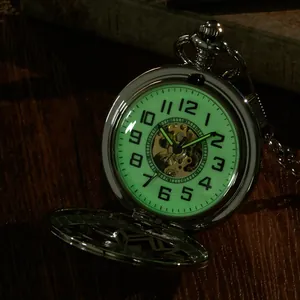 Gros plan montrant le cadran lumineux d'une montre de poche mécanique squelette vintage en argent.