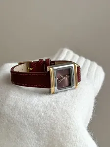 Détail d'une montre carrée vintage pour femme avec bracelet en cuir bordeaux sur tricot
