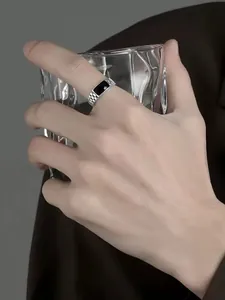 Close-up of a minimalist silver business ring with black inlay on a hand