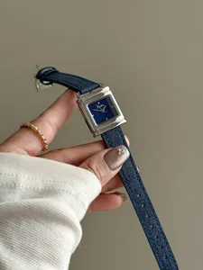Gros plan d'une montre carrée pour femme de style vintage avec bracelet bleu marine