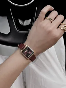 Gros plan d'une montre vintage en forme de cadenas avec bracelet en cuir bordeaux.