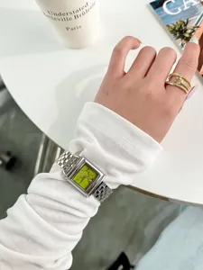 Gros plan d'une montre carrée vintage pour femme avec cadran vert et bracelet argenté