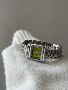 Gros plan d'une montre carrée vintage pour femme avec cadran vert sur tricot blanc