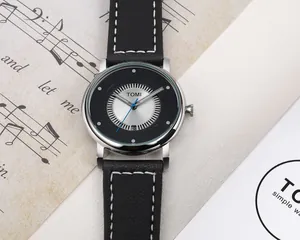 Primo piano dell'orologio TOMI minimalista con cinturino in pelle nera e data a ore 6.