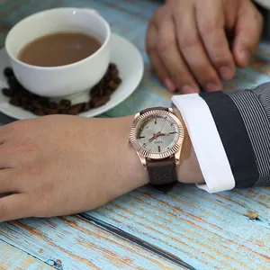 Gros plan d'une montre à quartz TOMI avec lunette cannelée portée au poignet dans un café