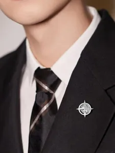 Detail view of a silver star compass brooch pinned to a professional black suit lapel