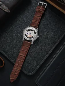 Detailansicht der TOMI Herren Quarzuhr mit braunem Lederarmband und Skelett-Zifferblatt