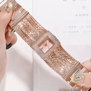 Gros plan d'une élégante montre carrée en or rose avec lunette en strass et chaîne