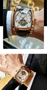 Gros plan d'une montre mécanique automatique carrée en or rose avec bracelet en cuir brun.