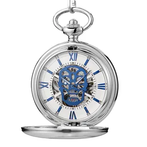 Détail macro d'une montre à gousset mécanique argentée avec cadran tête de mort bleu ajouré.